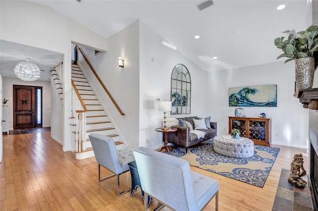 living room featuring light wood-style floors, visible vents, stairway, and a fireplace with flush hearth