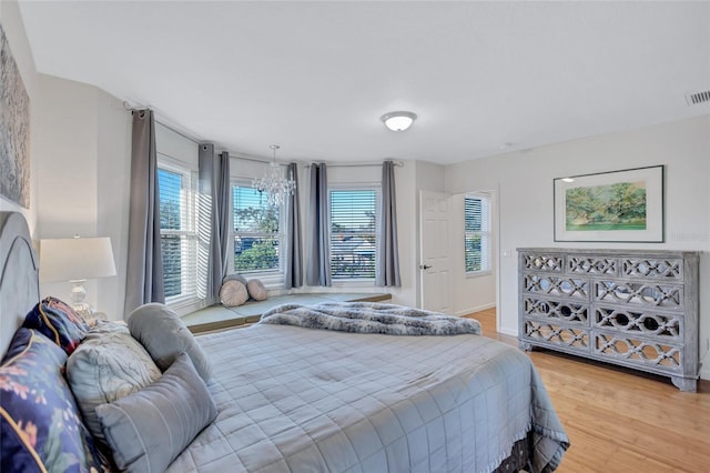 bedroom featuring a chandelier, visible vents, and wood finished floors