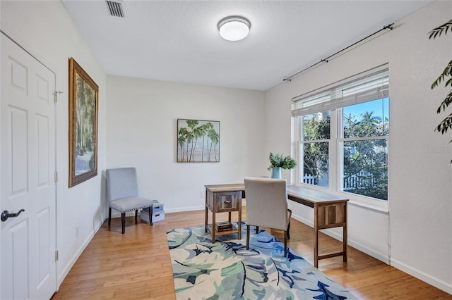 home office with light wood-style floors, baseboards, and visible vents