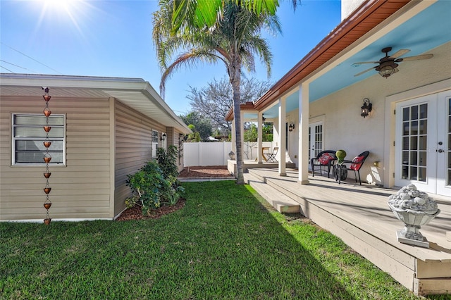 view of yard featuring fence, a ceiling fan, and french doors