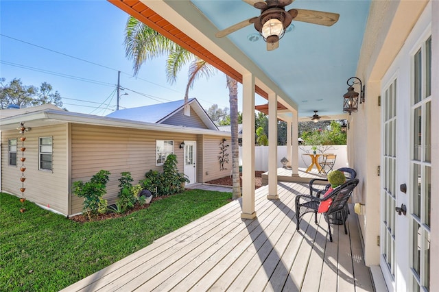 wooden terrace with ceiling fan, fence, and a yard