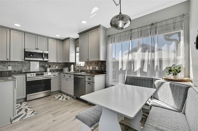 kitchen featuring hanging light fixtures, stainless steel appliances, gray cabinetry, and sink