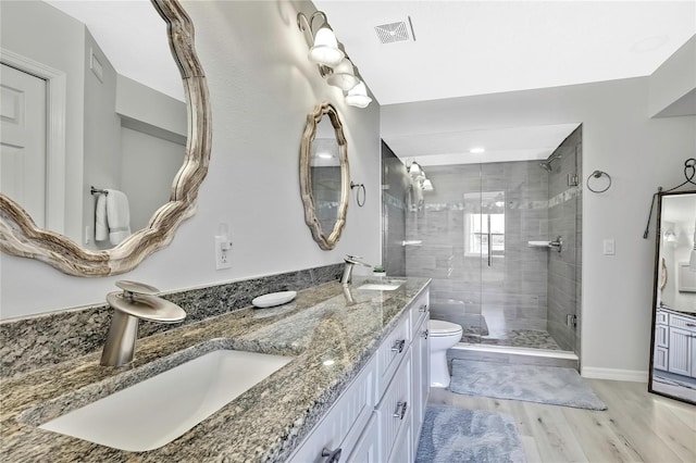 bathroom with toilet, vanity, wood-type flooring, and a shower with shower door