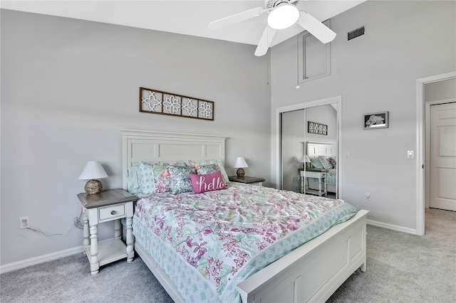 bedroom featuring ceiling fan, a closet, a towering ceiling, and light colored carpet