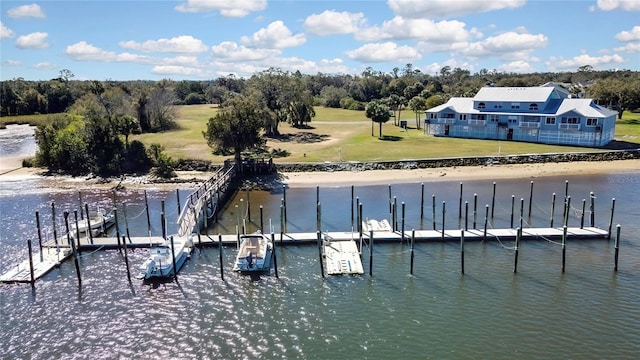 view of dock with a lawn and a water view