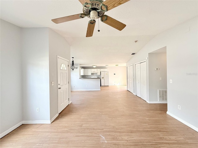 interior space featuring lofted ceiling, ceiling fan, visible vents, baseboards, and light wood-type flooring