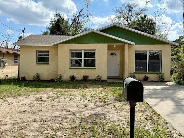 view of front of home with a shingled roof, fence, and stucco siding