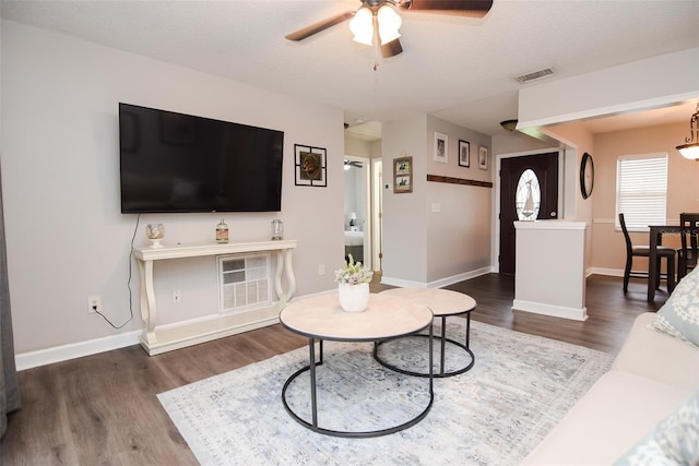 living room with a textured ceiling, dark wood-type flooring, and ceiling fan