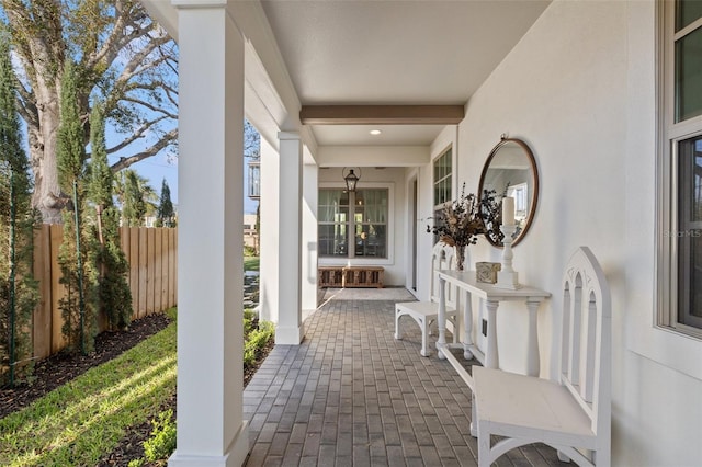 view of patio featuring a porch and fence