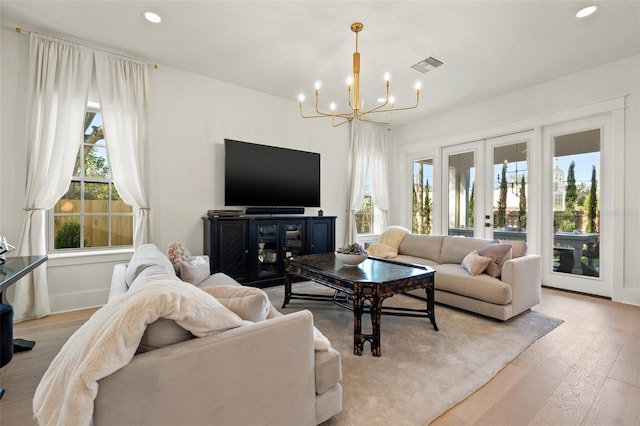 living area with a notable chandelier, recessed lighting, visible vents, light wood-style floors, and french doors