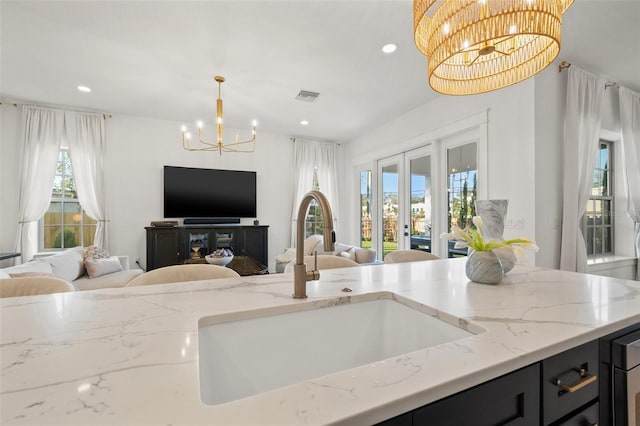 kitchen with pendant lighting, dark cabinetry, open floor plan, and an inviting chandelier