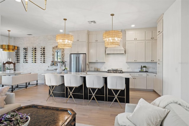 kitchen with open floor plan, visible vents, freestanding refrigerator, and pendant lighting