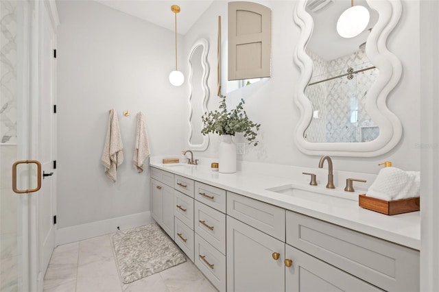 bathroom with marble finish floor, double vanity, a sink, and baseboards