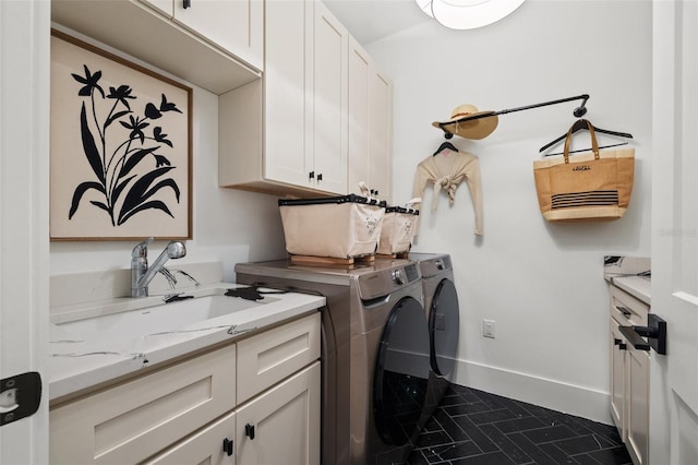 washroom featuring baseboards, cabinet space, a sink, and washing machine and clothes dryer