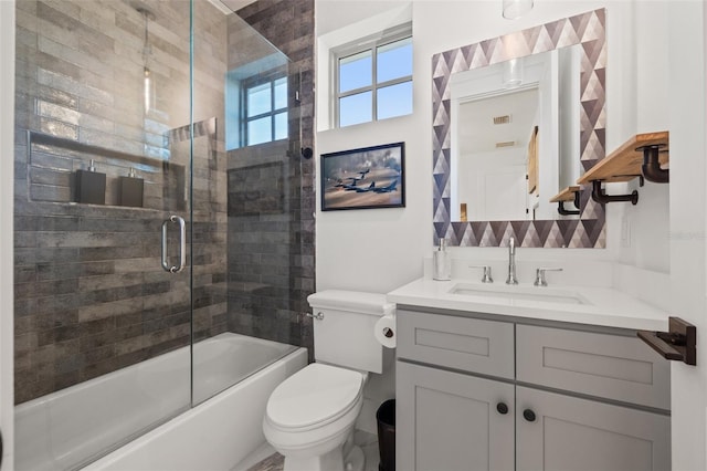 bathroom with enclosed tub / shower combo, vanity, and toilet