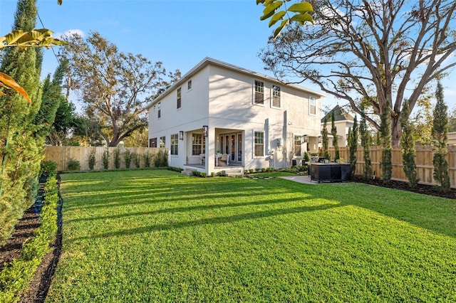 rear view of property featuring a patio, a lawn, a fenced backyard, and stucco siding