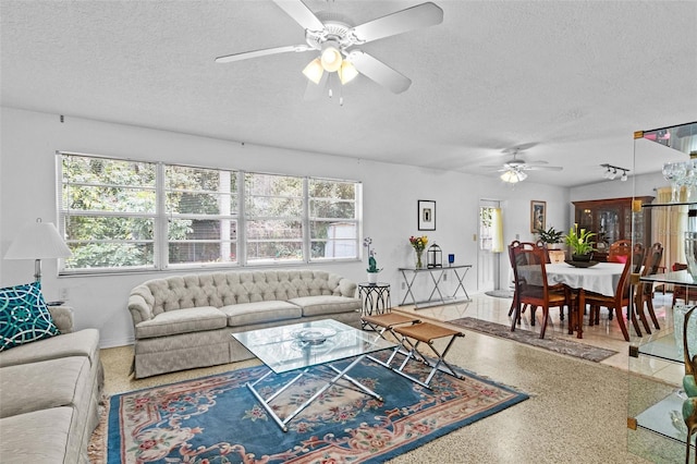 living area featuring a healthy amount of sunlight, ceiling fan, a textured ceiling, and speckled floor