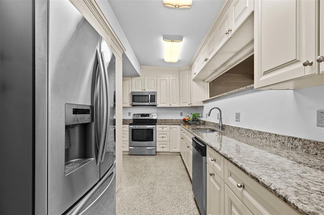 kitchen with light speckled floor, appliances with stainless steel finishes, a sink, and light stone counters