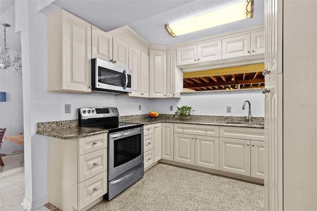 kitchen with stainless steel appliances, dark stone counters, and a sink