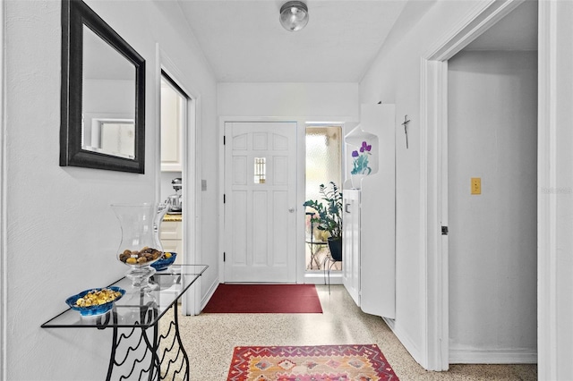 foyer with baseboards and speckled floor