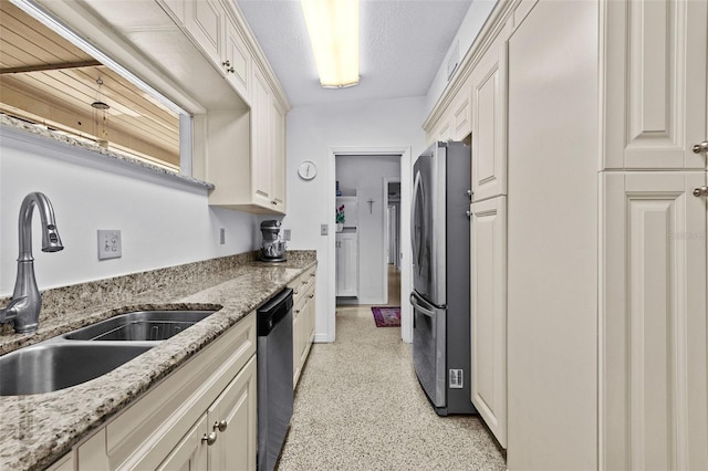 kitchen with light stone counters, light speckled floor, appliances with stainless steel finishes, a sink, and a textured ceiling