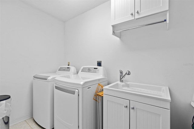 clothes washing area featuring baseboards, cabinet space, a sink, and washing machine and clothes dryer