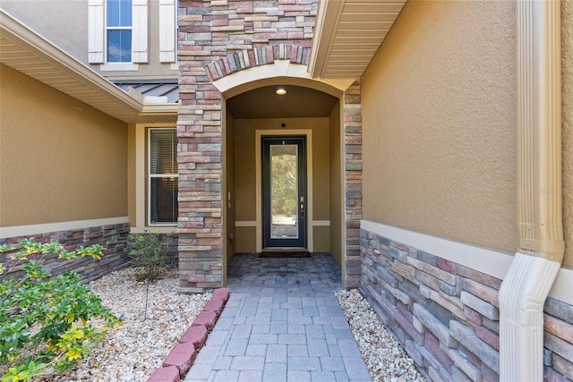 property entrance featuring stone siding and stucco siding