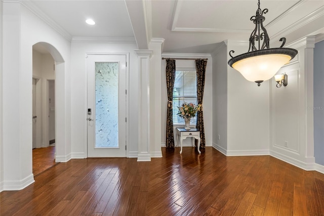 foyer entrance featuring arched walkways, baseboards, ornamental molding, wood-type flooring, and decorative columns