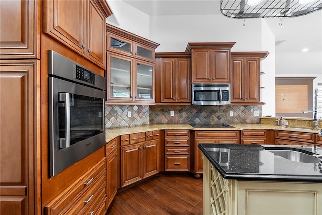 kitchen with stainless steel appliances, decorative backsplash, dark wood-type flooring, glass insert cabinets, and dark stone counters