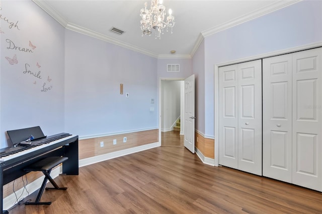 interior space with visible vents, an inviting chandelier, ornamental molding, wood finished floors, and baseboards