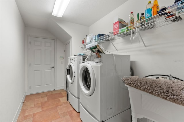 clothes washing area featuring laundry area, stone finish floor, independent washer and dryer, and baseboards