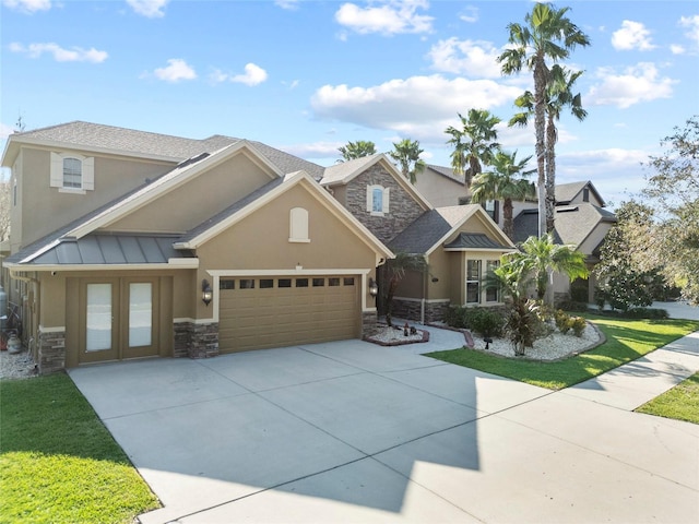 view of front of property with stone siding, a standing seam roof, concrete driveway, and stucco siding