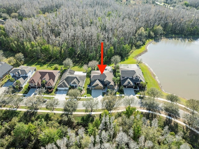 drone / aerial view with a residential view, a water view, and a wooded view