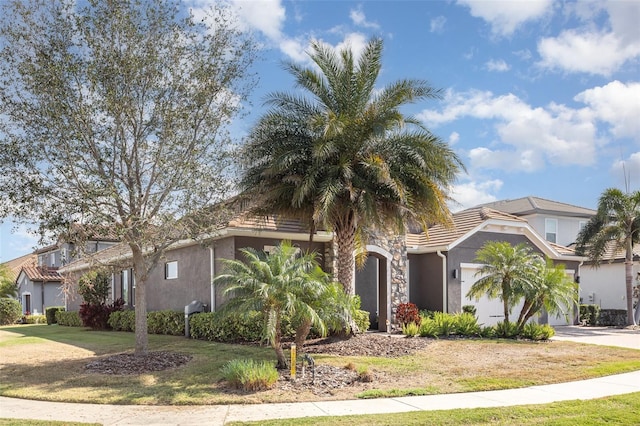 view of front facade featuring a garage, a tile roof, driveway, stucco siding, and a front yard