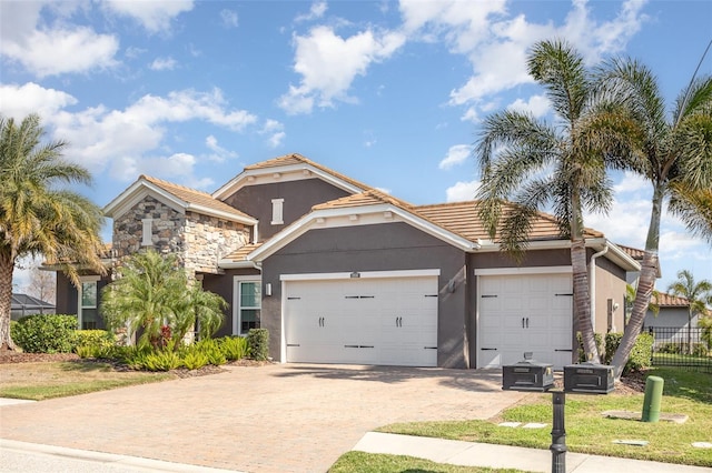 view of front of home with a garage, stone siding, decorative driveway, and stucco siding