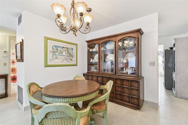 dining room featuring a textured ceiling, light tile patterned floors, baseboards, and an inviting chandelier