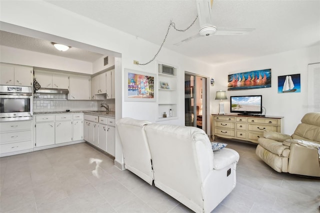 living room featuring a textured ceiling, ceiling fan, and visible vents