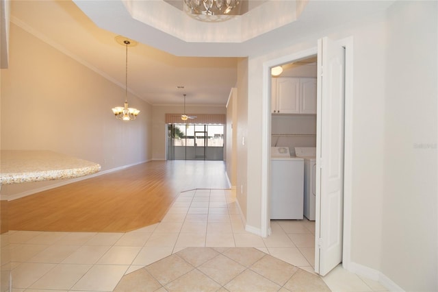 hall featuring washer and clothes dryer, light tile patterned floors, an inviting chandelier, ornamental molding, and baseboards