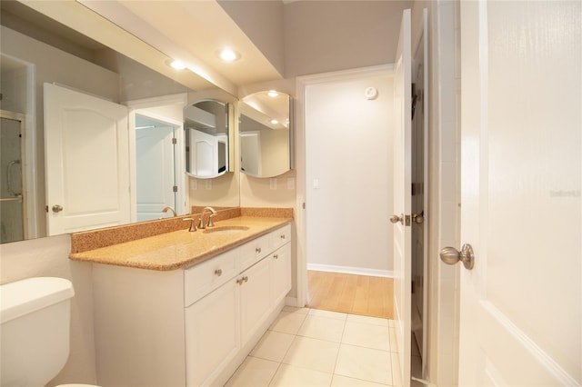 bathroom featuring baseboards, toilet, tile patterned floors, vanity, and recessed lighting