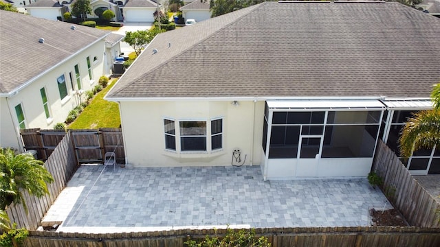 back of house with a sunroom, a patio area, a fenced backyard, and roof with shingles