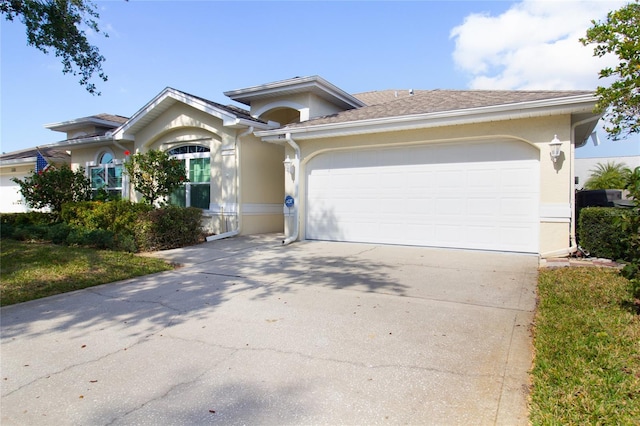 view of front facade with a garage, concrete driveway, and stucco siding