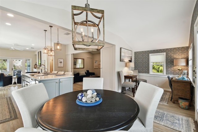 dining space with a wainscoted wall, wallpapered walls, recessed lighting, light wood finished floors, and lofted ceiling