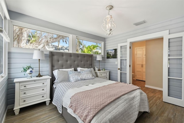 bedroom with a chandelier, visible vents, and wood finished floors