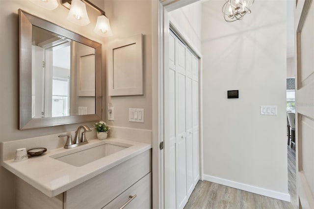 bathroom featuring vanity, an inviting chandelier, wood finished floors, and baseboards