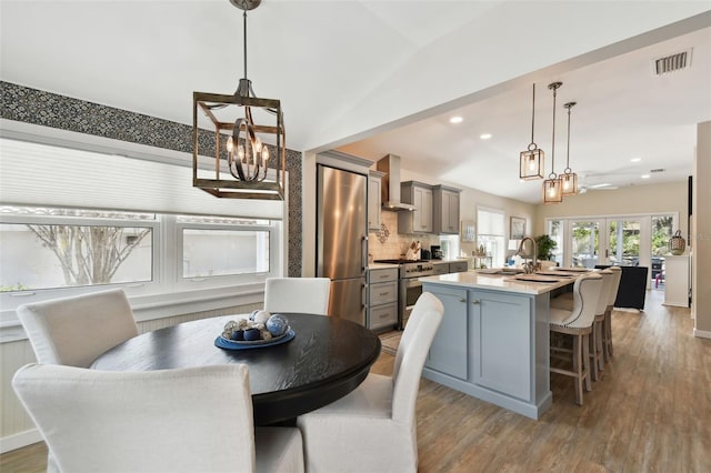 dining area featuring wood finished floors, recessed lighting, french doors, an inviting chandelier, and lofted ceiling