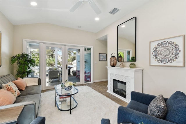 living room with visible vents, vaulted ceiling, recessed lighting, a tile fireplace, and wood finished floors