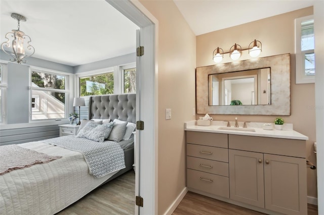 bathroom with vanity, wood finished floors, baseboards, and a chandelier