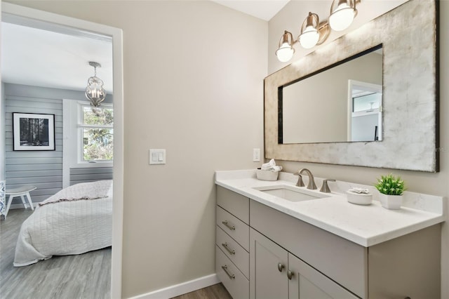 ensuite bathroom featuring connected bathroom, baseboards, wood finished floors, and vanity