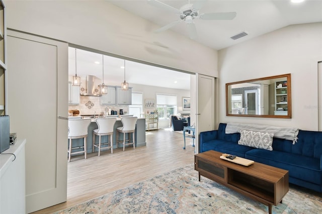 living area with visible vents, lofted ceiling, recessed lighting, ceiling fan, and light wood-style floors