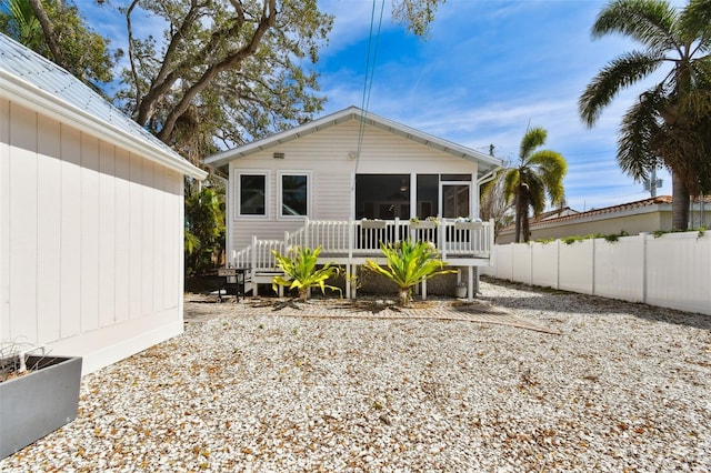 rear view of property featuring a sunroom and fence